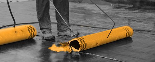 A worker rolling a waterproofing membrane out across a slab