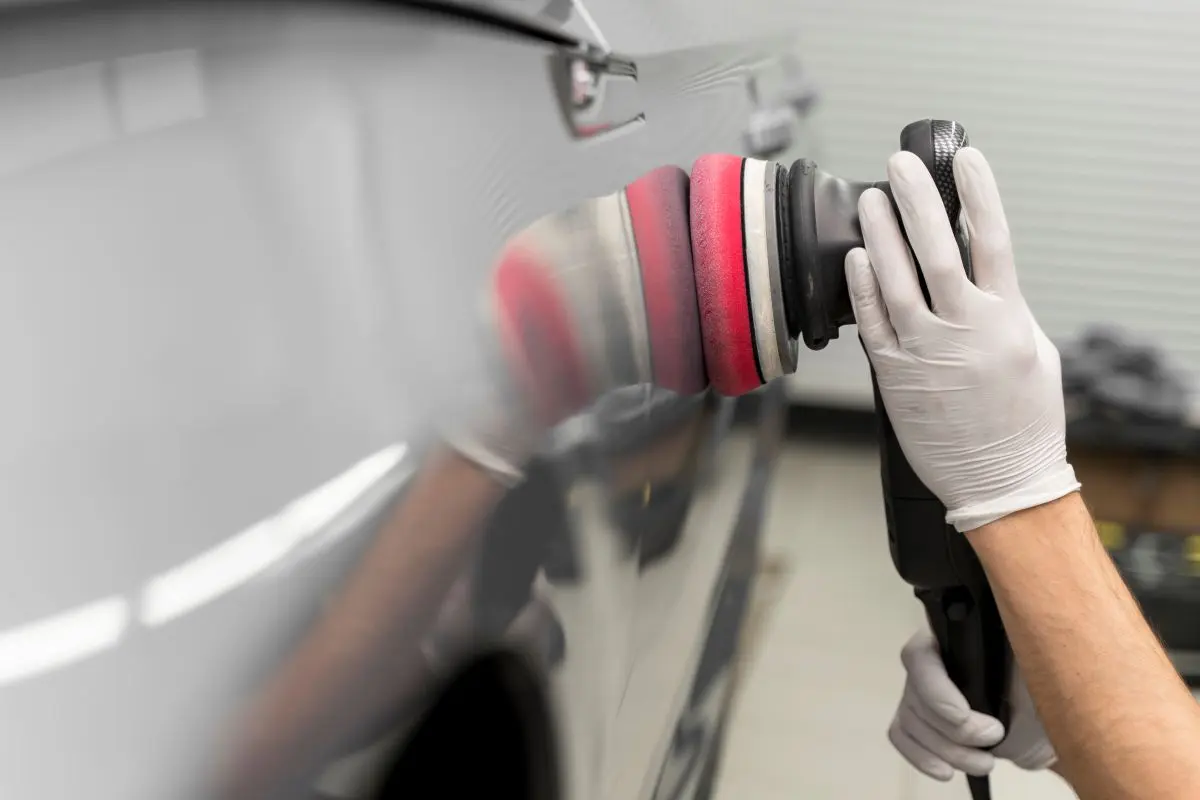 Machine polisher refining a car panel