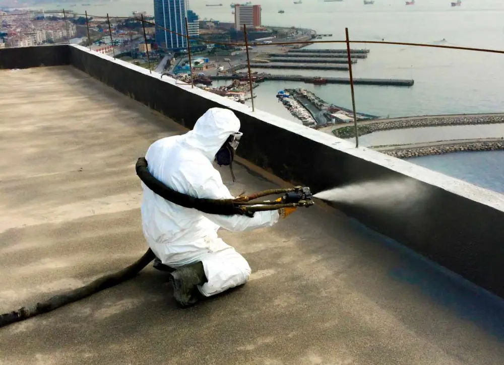 An SMCC technician spray-applying waterproofing to a rooftop