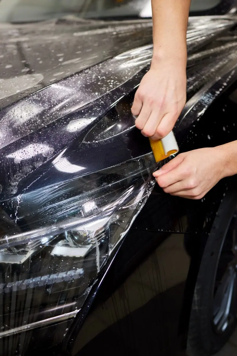 Clear protective film being applied to a car hood
