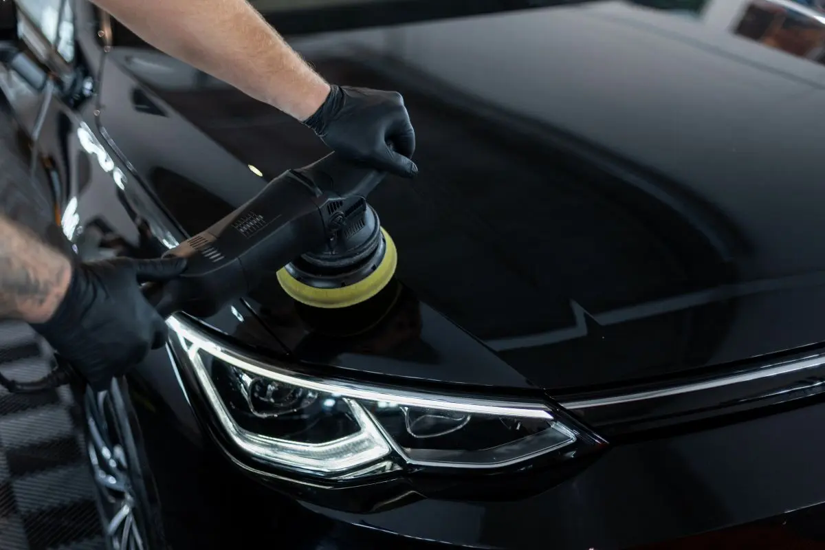 Polisher working scratches out of a black car panel
