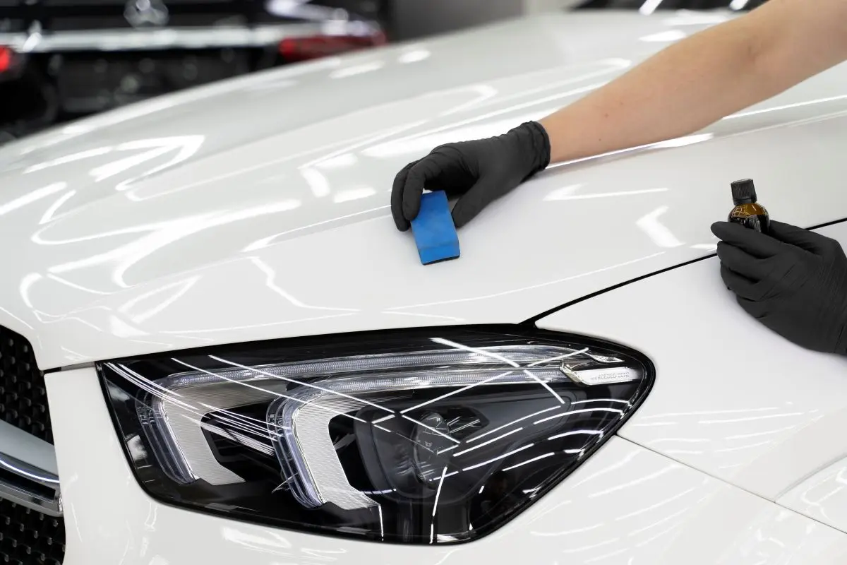 Ceramic coating being applied to a white car fender with an applicator block