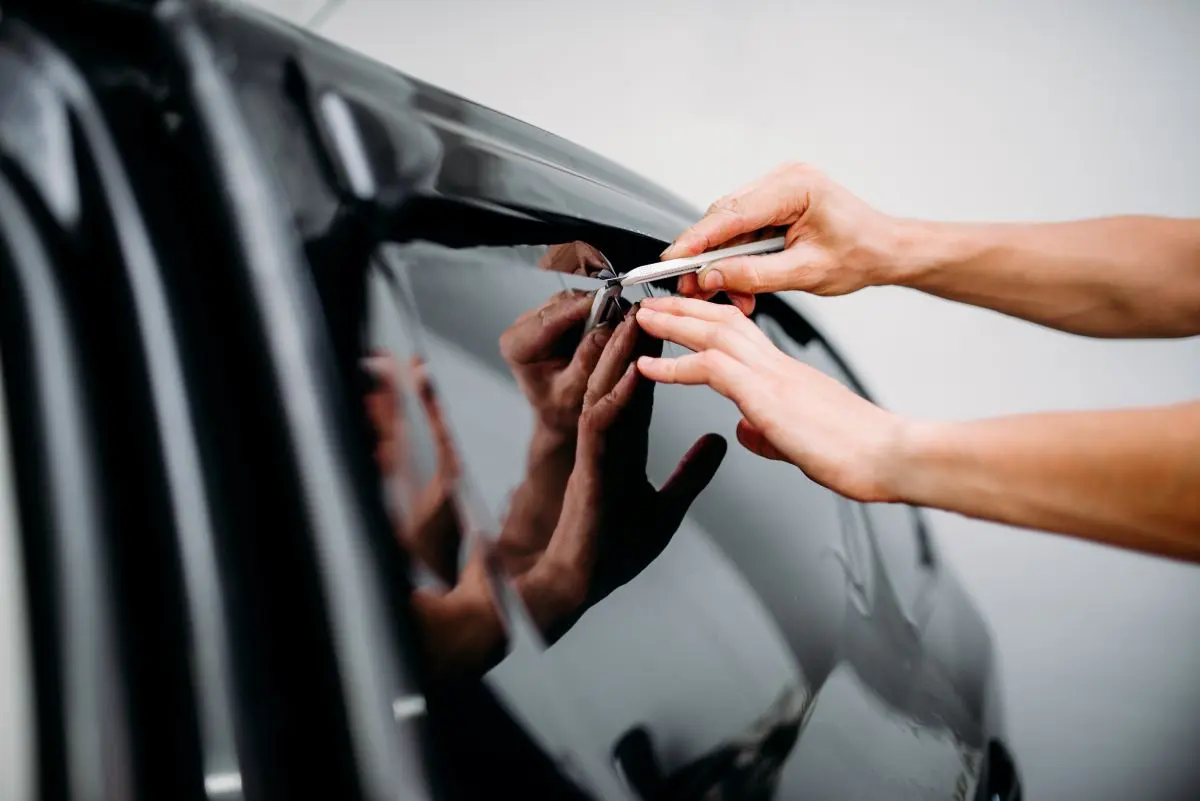 Technician squeegeeing tint film onto a car window